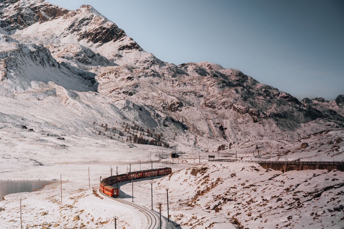 Alpine train tracks through snow with mountain backdrop