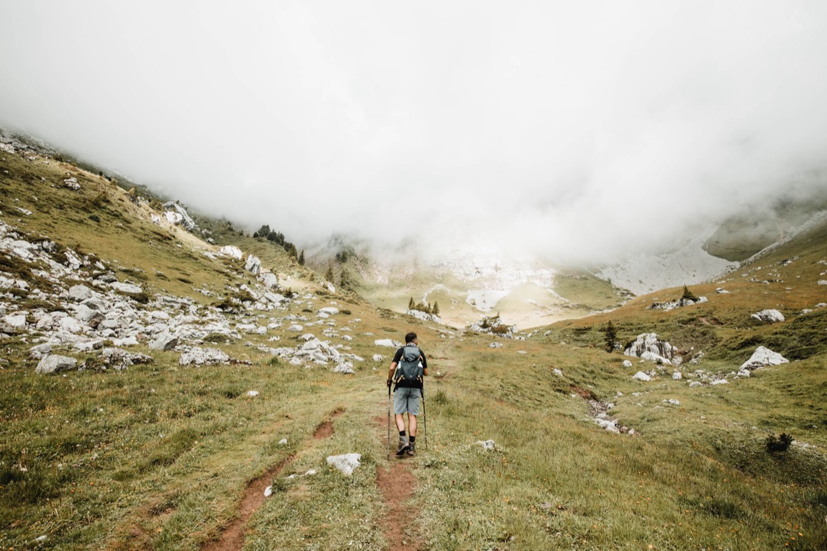 Hiker resting on Alps trail with backpack and elevation signs