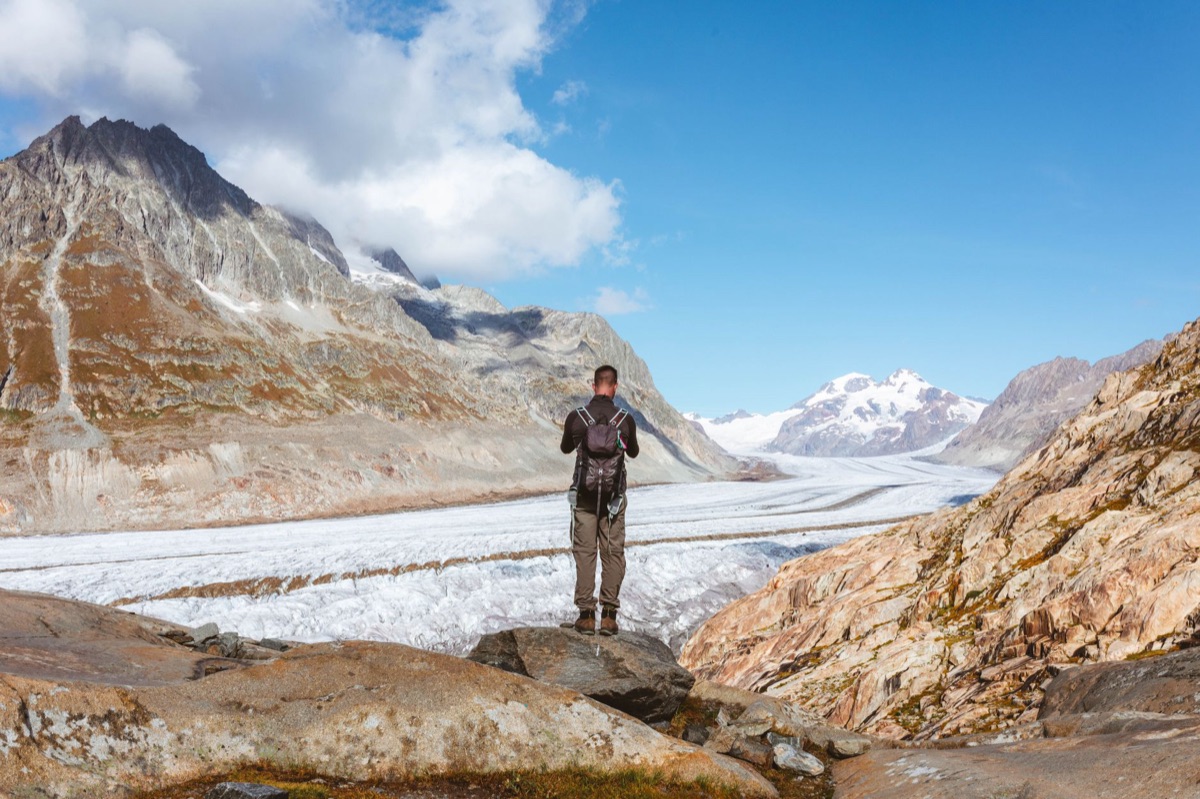 Hiker at alpine trail with backpack and map